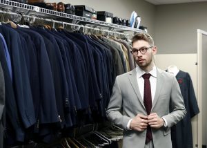 A student models a grey suit and crimson tie in the Crimson Closet