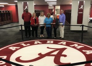 Employer Advisory Board members stand in front of the UA logo in a locker room